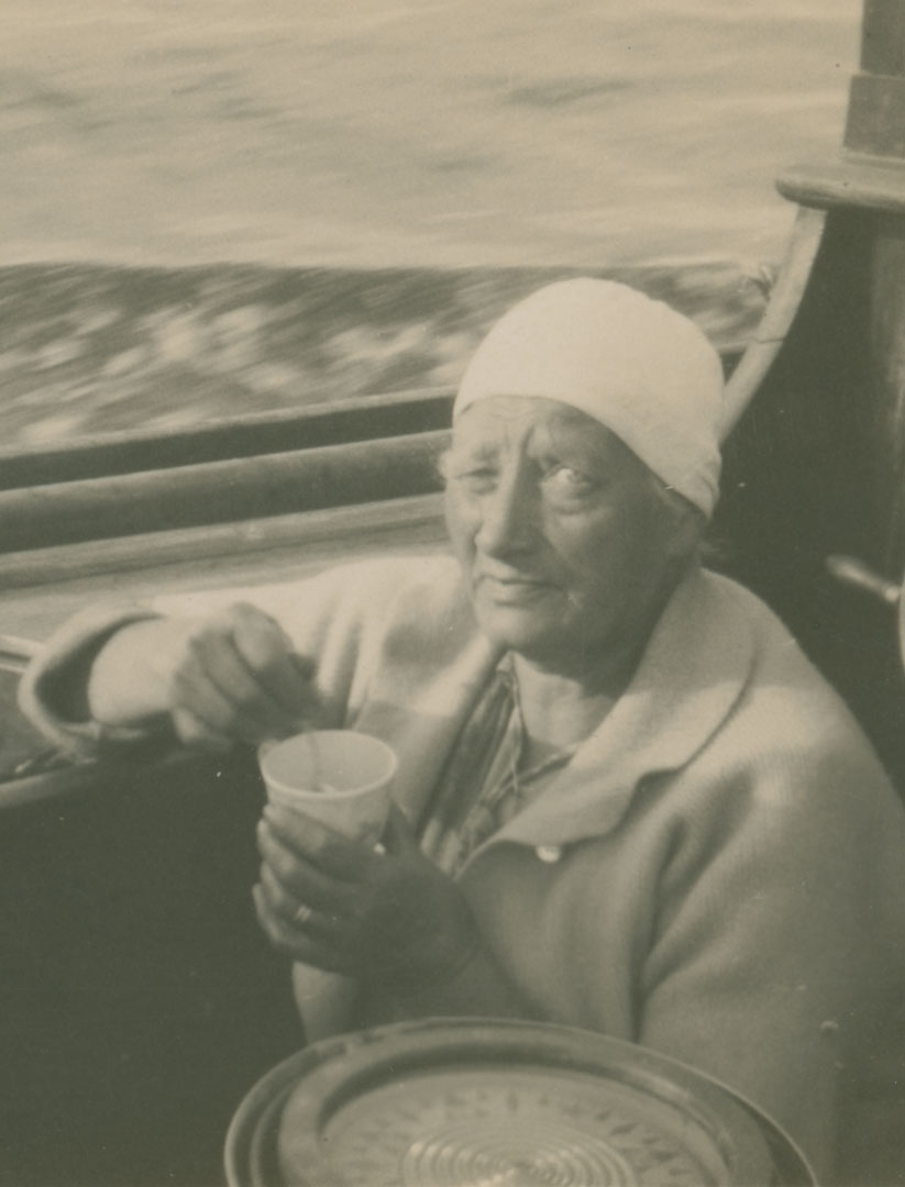 Fru Rehnberg sitter i båten och rör runt i en kopp med kaffe
