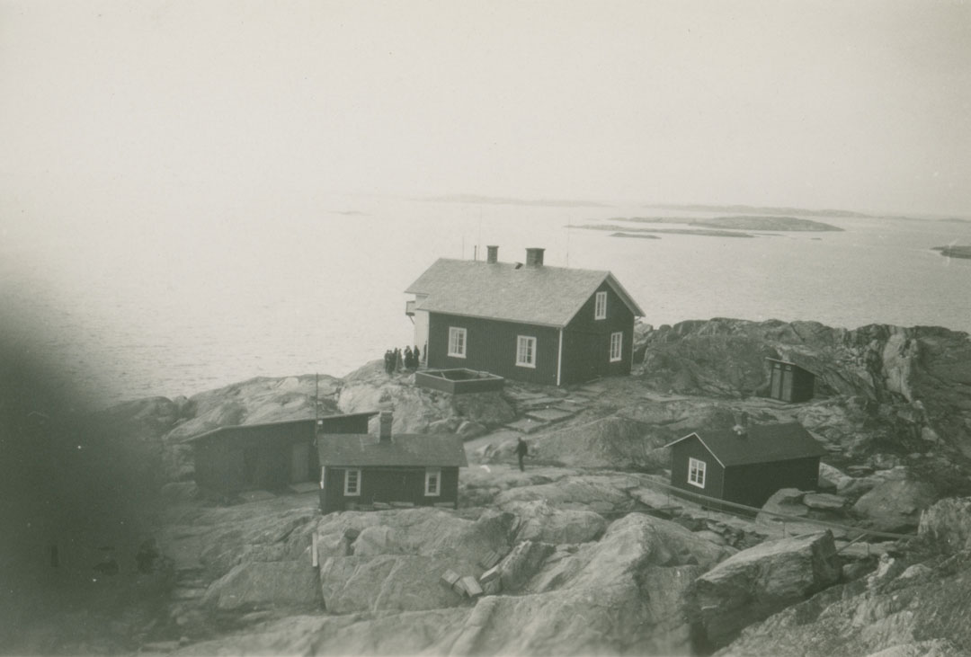 Islandsbergs fyrplats. En grupp människor står på klipporna nedanför själva huset.